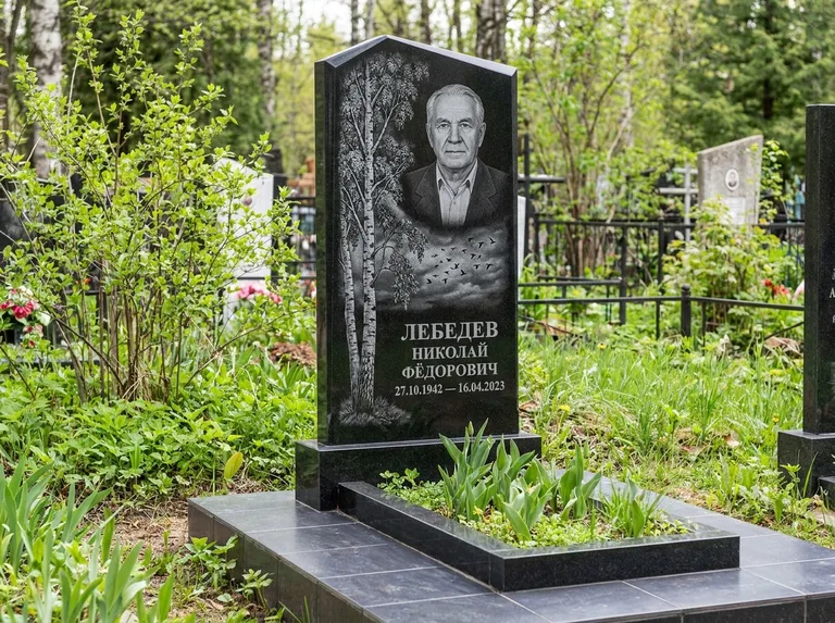 Памятник с гравировкой берёзы: вертикальная стела со скошенным верхом — берёза и стая птиц в небе, гранитный цоколь с тёмной плиткой, работа «Лебедев» в Иркутске