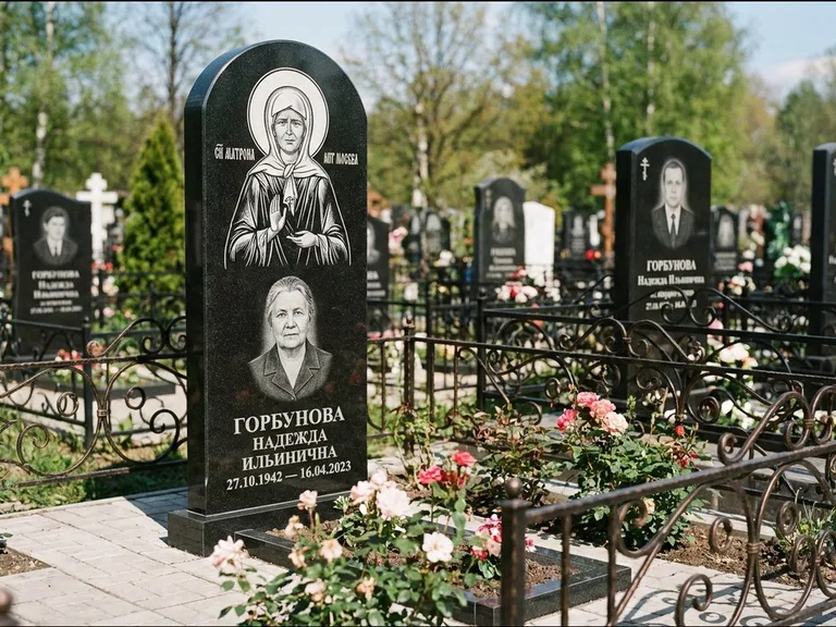 Памятник с гравировкой иконы: стела с арочным верхом и киотом под образ — гравировка образа Матроны Московской, гранитный цоколь с тёмной плиткой, работа «Ковалёв» в Иркутске
