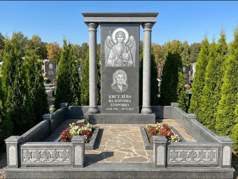 Памятник с гравировкой иконы: массивная стела с двускатным навершием-домиком — гравировка Николая Чудотворца, живая изгородь из туи, работа «Журавлёв» в Иркутске