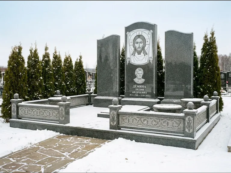 Памятник с гравировкой иконы: узкая вертикальная стела-пилон с ликом — икона в резной рамке-киоте, открытая лужайка без ограды, работа «Одинцов» в Иркутске