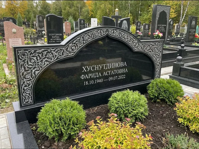Мусульманский памятник: вытянутая горизонтальная семейная стела с аркой — белая гравировка силуэта мечети с минаретами, участок с декоративными кустами, работа «Зарипова» в Иркутске
