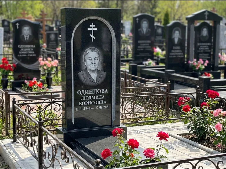 Памятник из чёрного гранита — скромная невысокая стела с крестом с терновым венцом, работа «Лаврентьева» в Иркутске